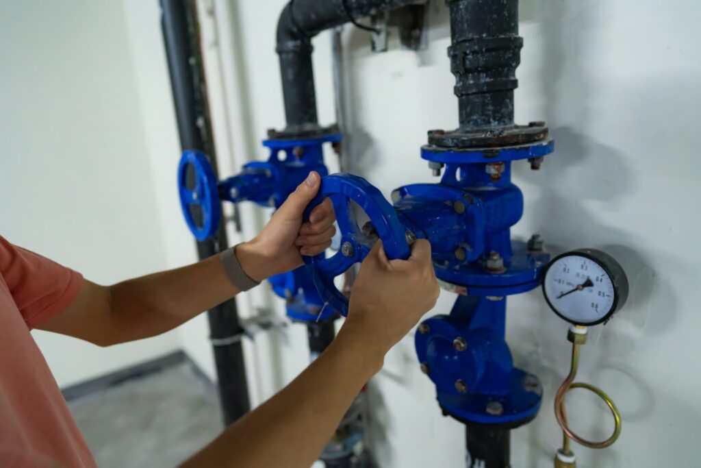 Person operating a blue valve in a plumbing system, illustrating gas line leak detection and safety measures relevant to homeowners in Dallas, TX.